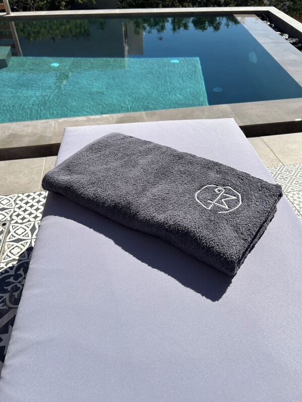 A towel with a logo on a white surface near a pool.