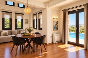 Ein modernes Wohnzimmer mit Essbereich, großen Fenstern und Blick auf einen Pool.