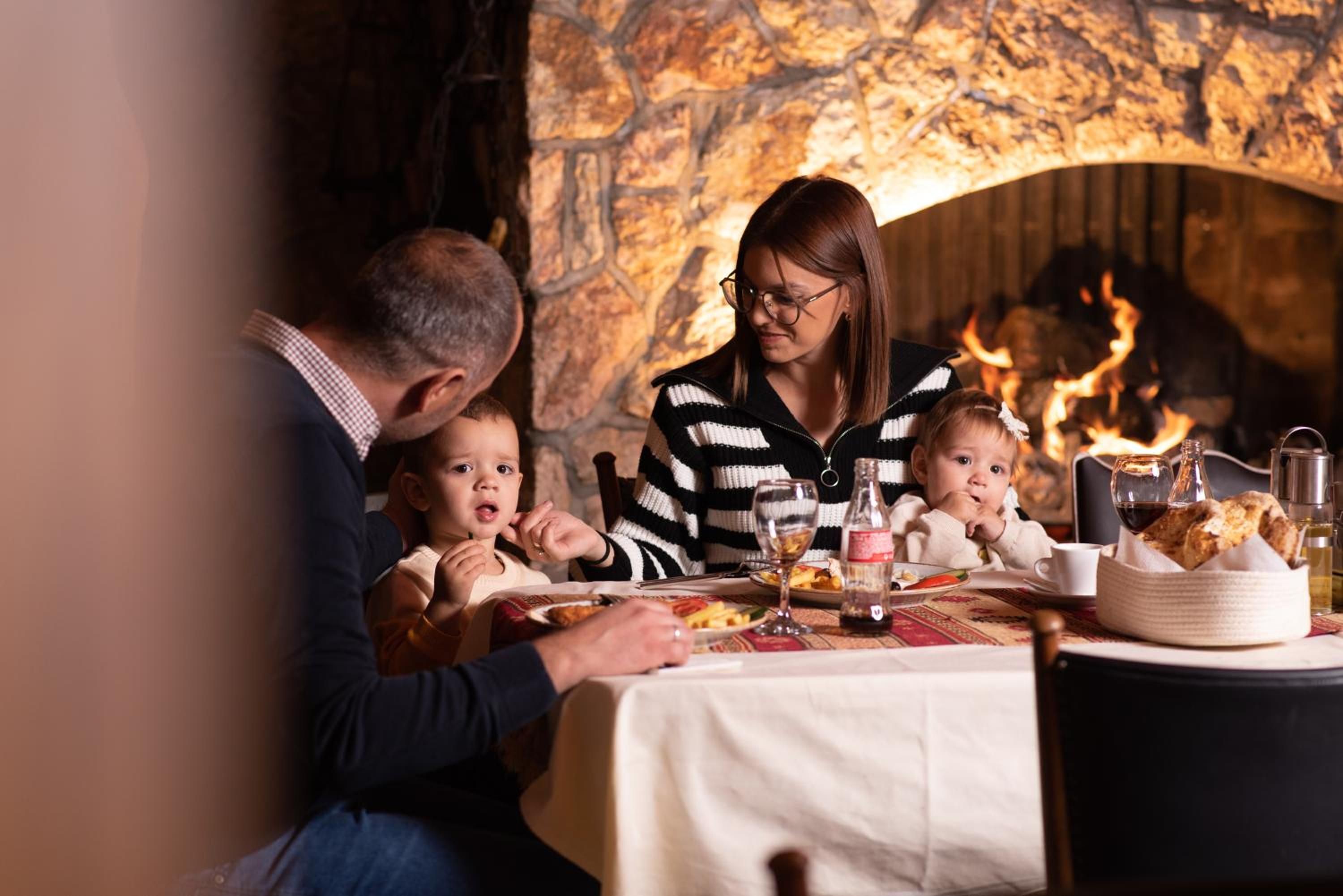 A family dining at a table with a stone fireplace in the background.