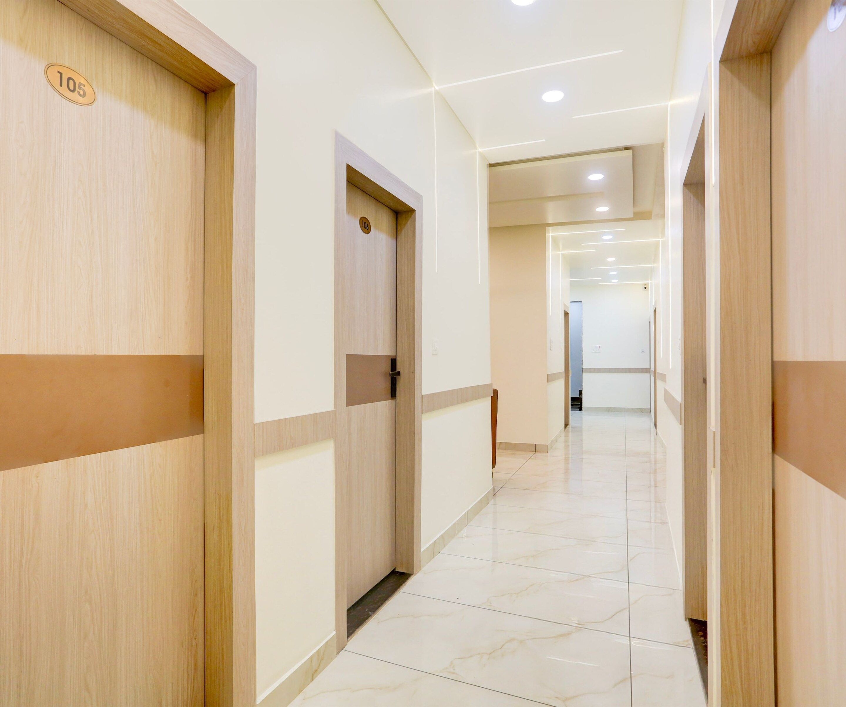Un pasillo de hotel con paneles de madera, puertas numeradas y suelo de baldosas.