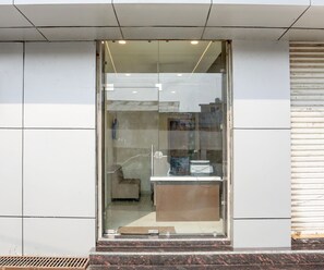 Une entrée moderne avec une porte en verre, une petite marche menant à celle-ci et une grille métallique en bas.
