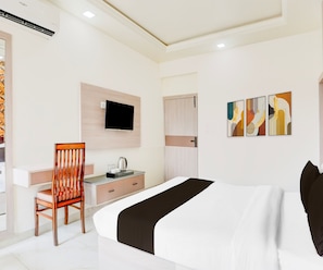 A hotel room with a bed, a desk, a chair, a television, and artwork on the wall.