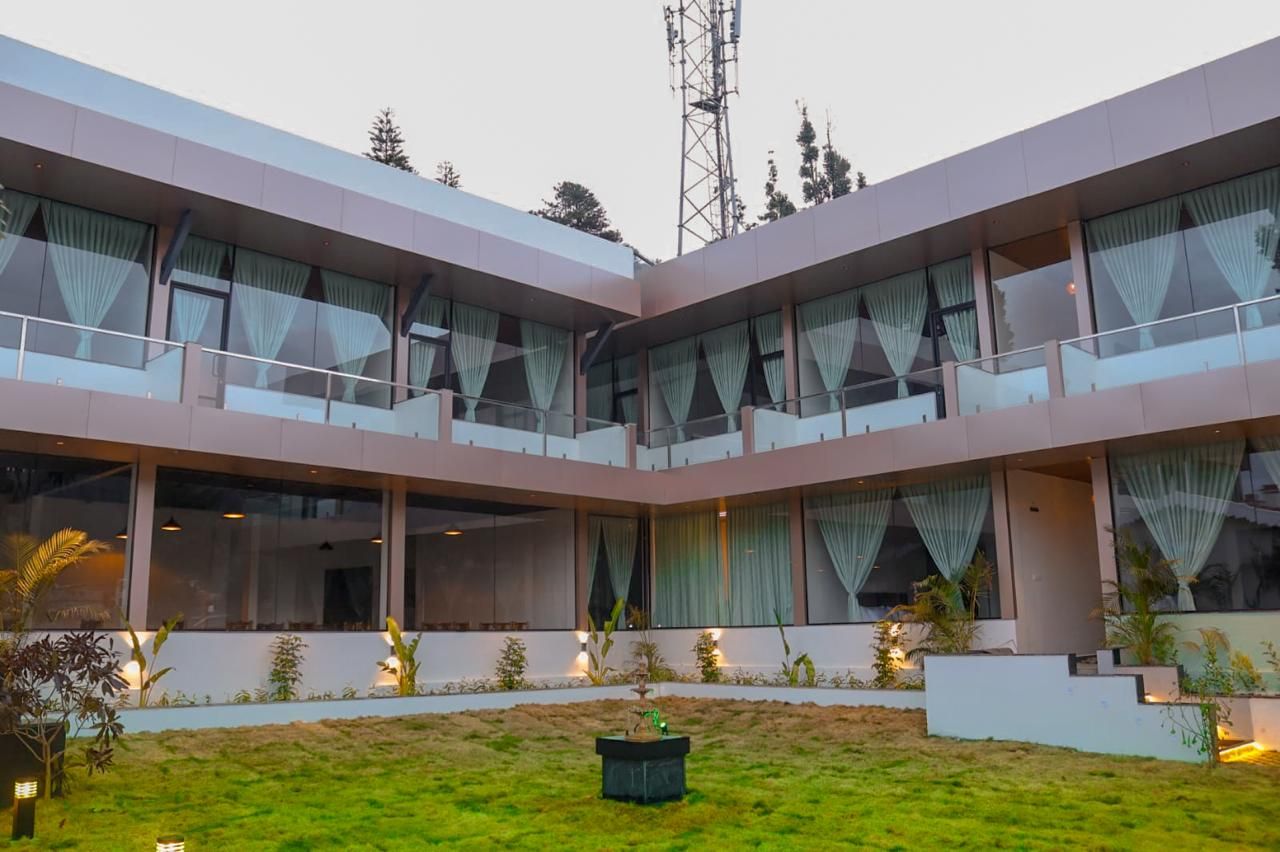 Um edifício moderno com várias varandas, janelas amplas e um jardim bem cuidado.