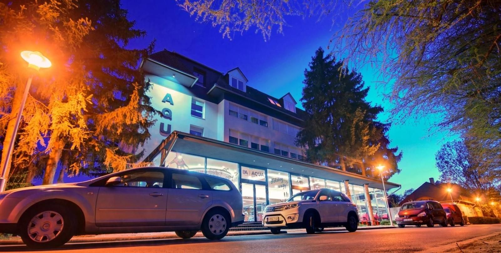 A hotel with a visible sign reading 'BAQUA' and a car parked in front.