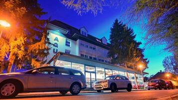 A hotel with a visible sign reading 'BAQUA' and a car parked in front.