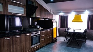 Une cuisine moderne avec des meubles en bois, un plan de travail noir et un coin repas comprenant une table et des chaises.