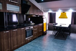 Una cocina moderna con armarios de madera, encimera negra y una zona de comedor con mesa y sillas.