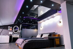 A modern bedroom with a bed, bedside table, and a mirror.