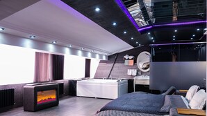 Une chambre à coucher moderne avec un grand lit, une baignoire et un téléviseur.