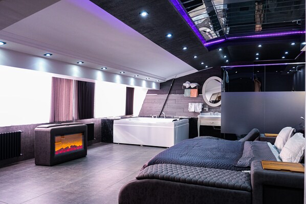 A modern bedroom with a large bed, a bathtub, and a television.