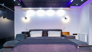 Une chambre moderne avec un grand lit, des tables de chevet et des lampes fixées au mur.