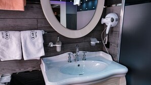 Une salle de bain avec un lavabo blanc, un miroir et deux serviettes accrochées au mur.