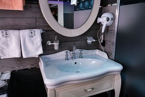 Un baño con un lavabo blanco, un espejo y dos toallas colgadas en la pared.