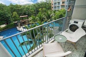 A balcony with a view of a swimming pool, a small table, and a chair. - Apartment Near Nai Yang Beach - Pool View 1BR Condo with Gym & Fast Wi-Fi - B403 (Tambon Sa Khu)