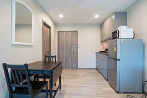 A compact kitchen with a dining table and chairs, a refrigerator, and cabinets. - Apartment Near Nai Yang Beach - Pool View 1BR Condo with Gym & Fast Wi-Fi - B403 (Tambon Sa Khu)