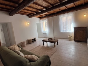 A room with a wooden ceiling, a green sofa, a small table with a bowl, and a cabinet. - Nice downtown apartment (Cavaillon)