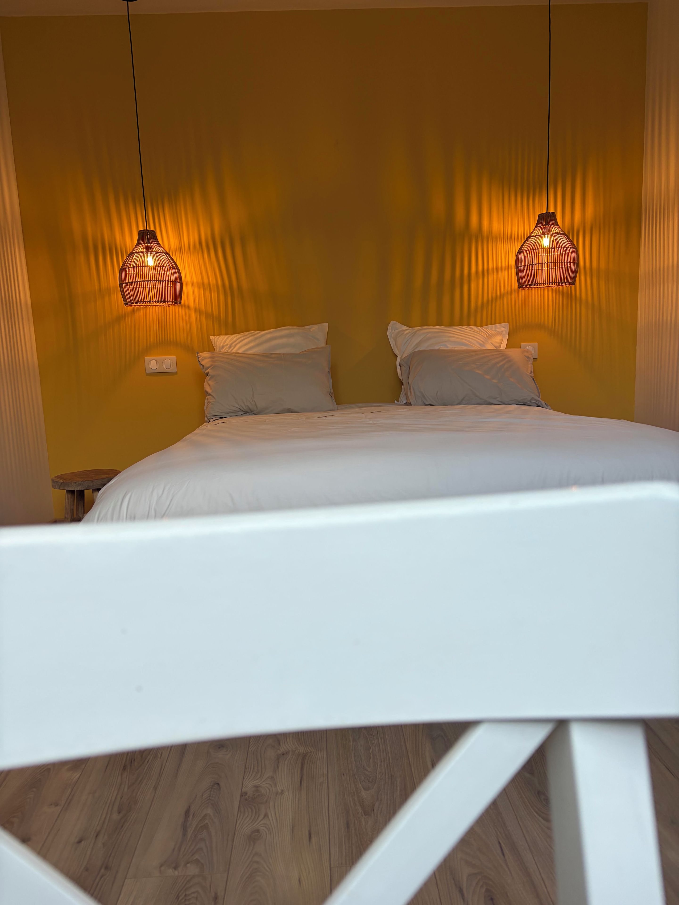A bed with white bedding, two bedside lamps, and a wooden floor.