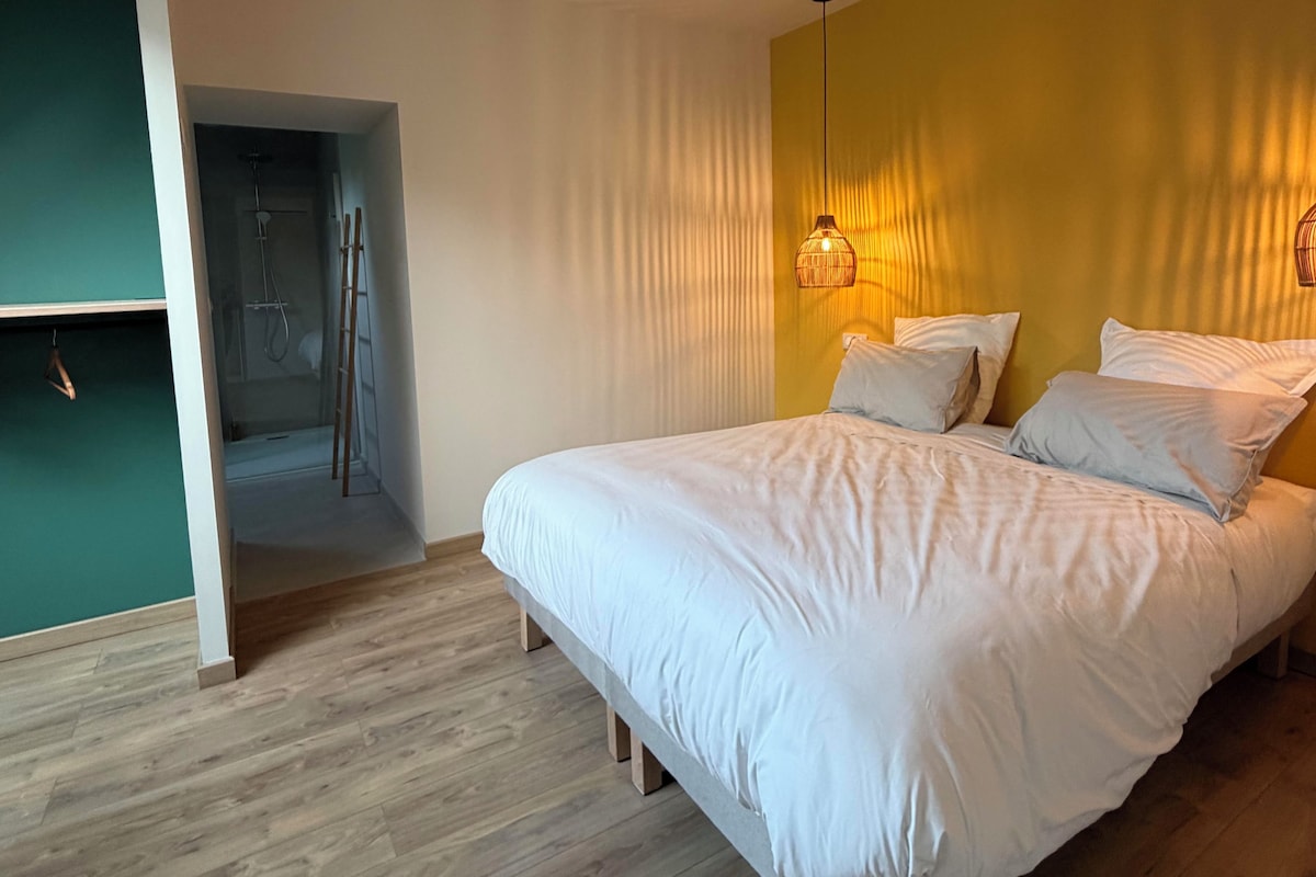 A bedroom with a bed, a hanging light fixture, and a wooden floor.