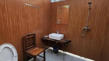 Un baño pequeño con tocador de madera, inodoro y ducha.