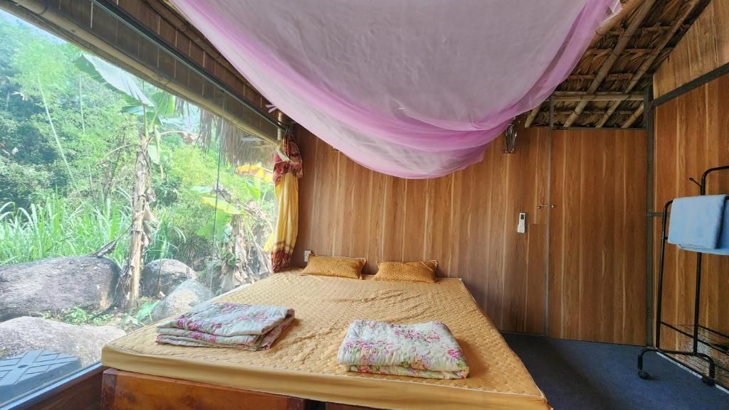 Ein Zimmer mit einem Bett, einem Schreibtisch und einem Fenster mit Blick auf Grünflächen.