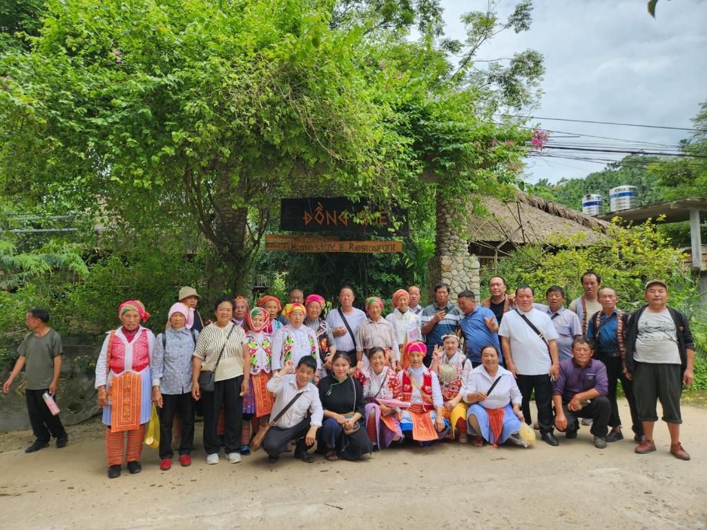 Un grupo de personas posando frente a un edificio rústico con un letrero que dice 'Bong's Home Stay & Restaurant'.