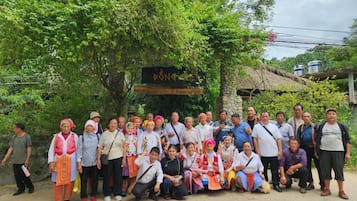 Un grupo de personas posando frente a un edificio rústico con un letrero que dice 'Bong's Home Stay & Restaurant'.