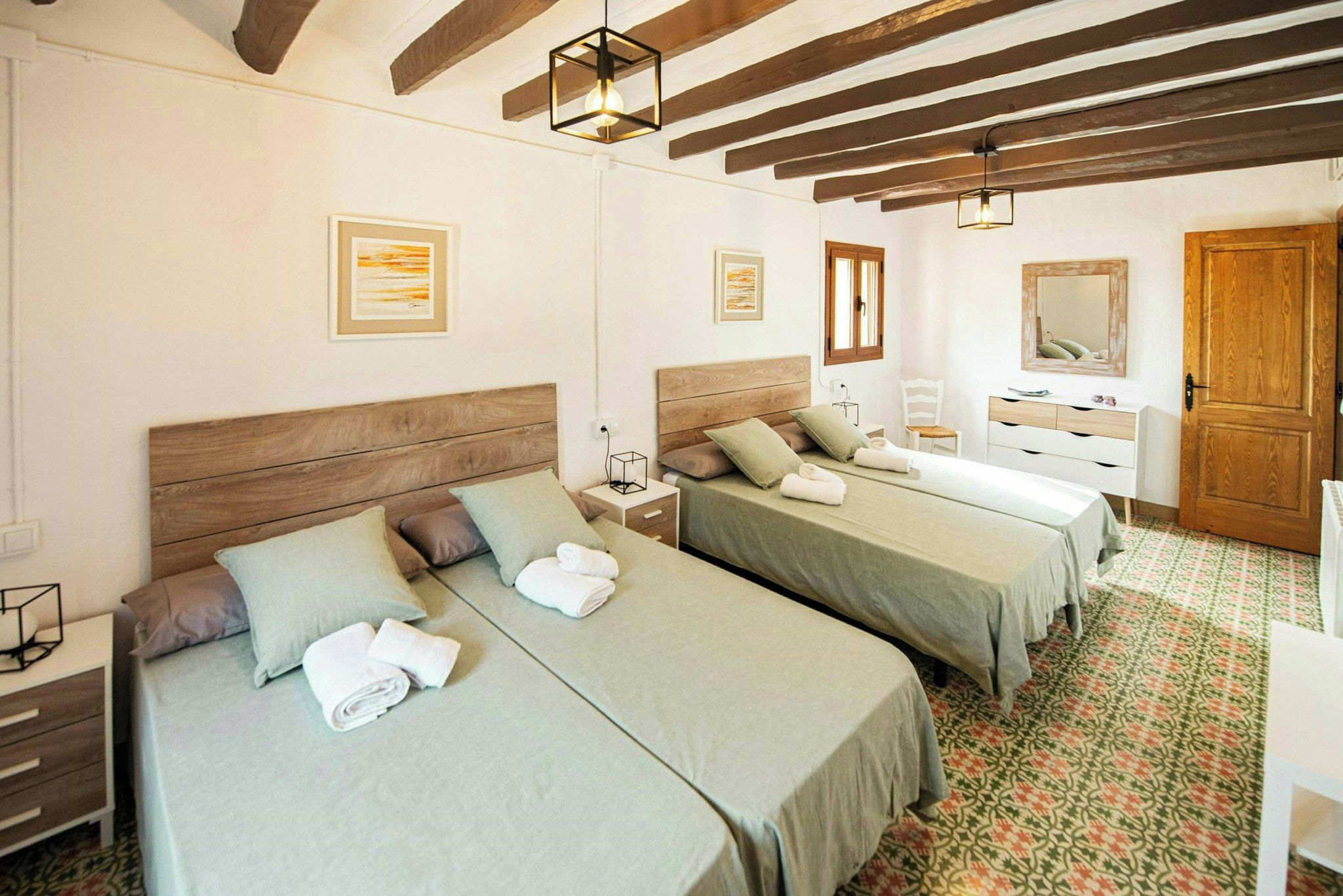 A hotel room with two beds, a wooden ceiling, a mirror, and a patterned floor.