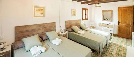 A hotel room with two beds, a wooden ceiling, a mirror, and a patterned floor.