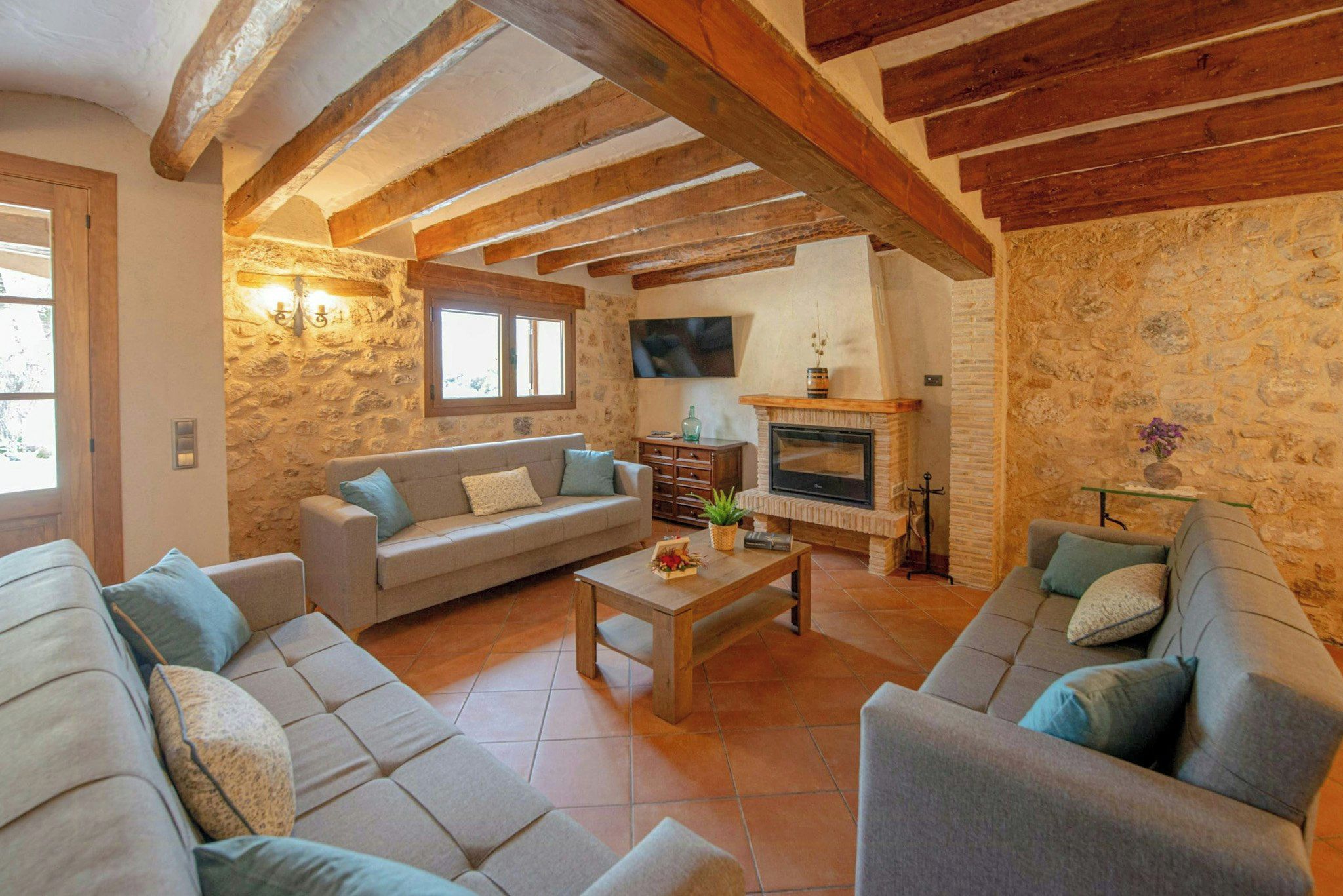 A cozy living room with a stone wall, a fireplace, and a sofa.