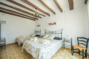 A room with two beds, a chair, a table, and a chandelier. - Masía among vineyards with pool in Catalonia (El Pla de Manlleu)