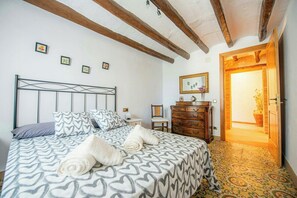 Une chambre à coucher comprenant un lit, une commode et une porte donnant sur une autre pièce.