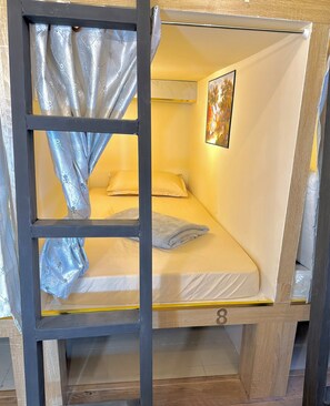 Ein Einzelbett mit Kopfteil, einem Vorhang und einem Gemälde an der Wand.