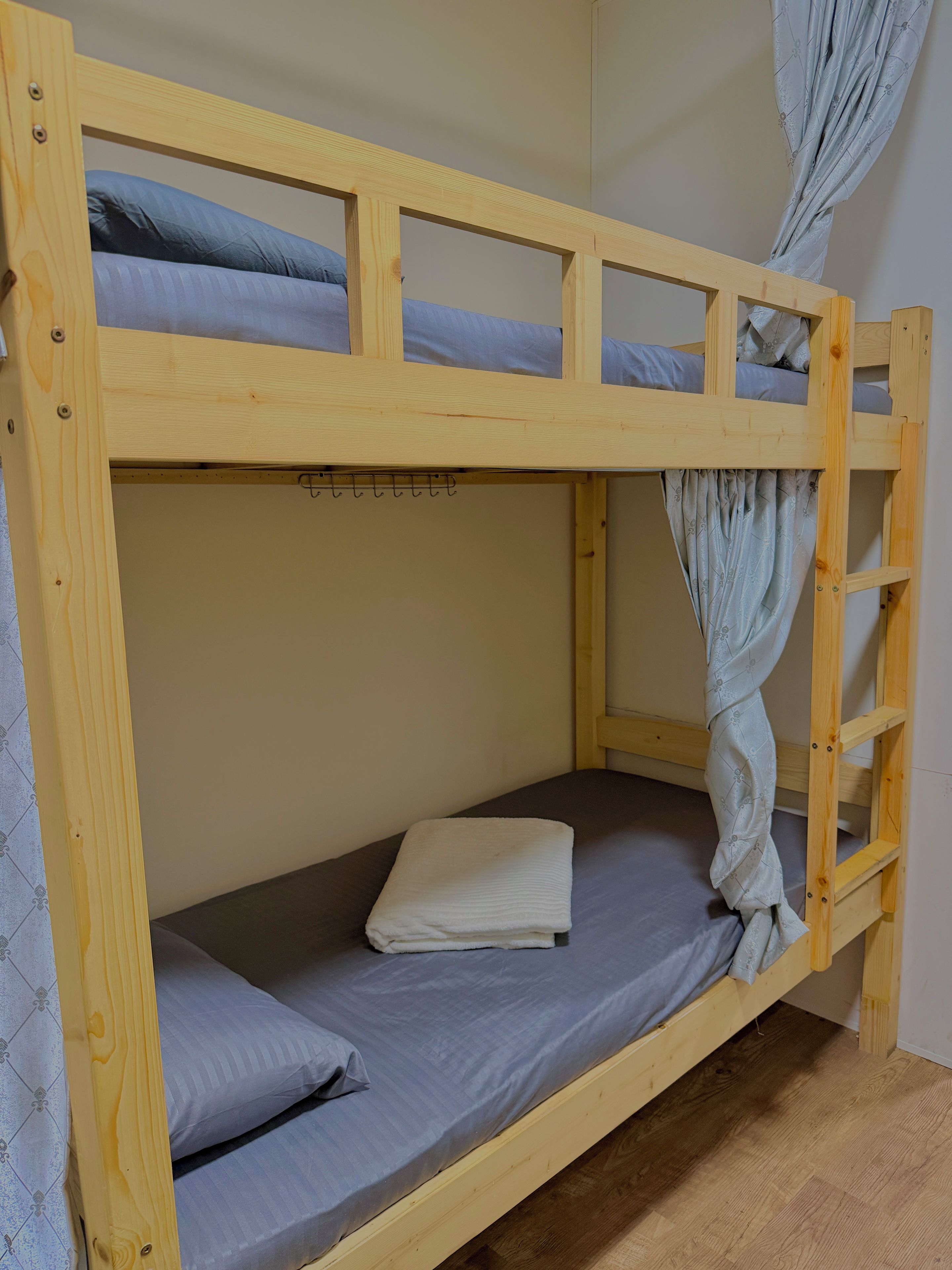 Ein Stockbett mit einer Leiter, einem Vorhang und einem gefalteten Handtuch auf der unteren Liege.