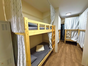Une chambre avec un lit superposé en bois, un lit inférieur doté d’un matelas et d’oreillers, et une échelle.