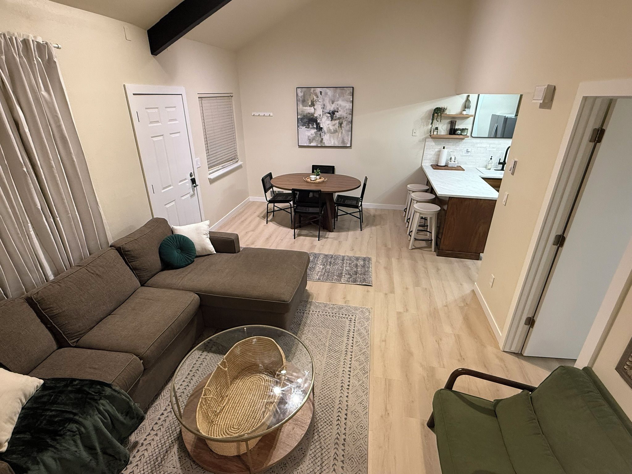 Un espacio habitable compacto con sofá, una mesa de comedor redonda y una zona de kitchenette.