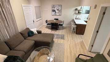 Un espacio habitable compacto con sofá, una mesa de comedor redonda y una zona de kitchenette.