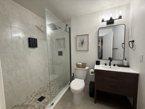 Een moderne badkamer met een douchecabine van glas, een toilet en een wastafel met spiegel.