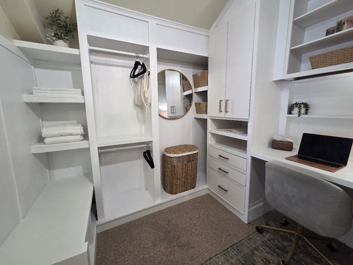 A walk-in closet with open shelving, a mirror, and a laptop on a desk.