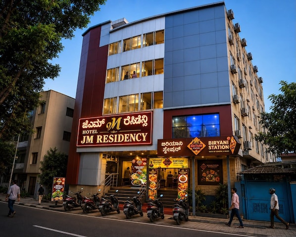 A hotel with a prominent sign for 'JM Residency' and a nearby 'Biryani Station' restaurant. - Hotel JM Residency (Bengaluru)