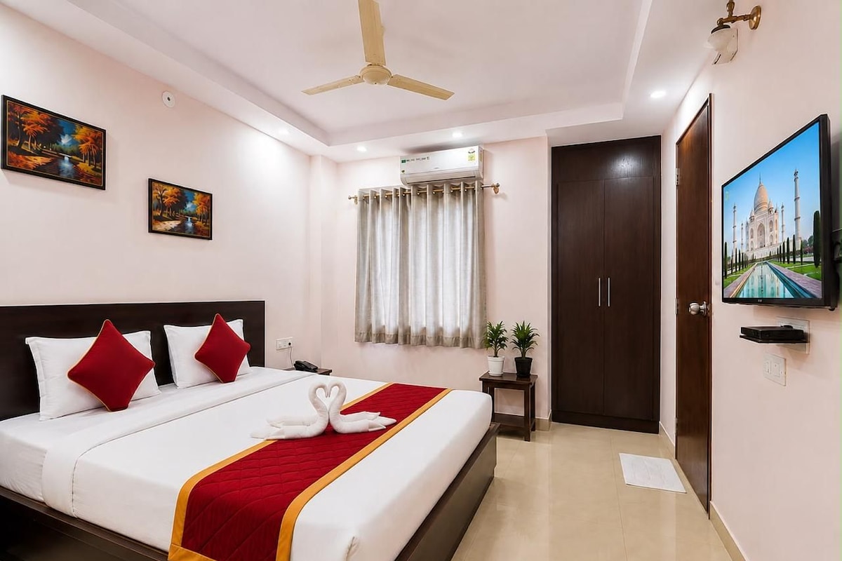 A hotel room with a bed, a ceiling fan, a television, and a door.