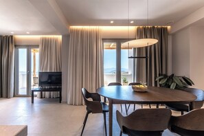 Ein modernes Wohnzimmer mit Essbereich, einem Flachbildfernseher und einem Balkon mit Vorhängen.