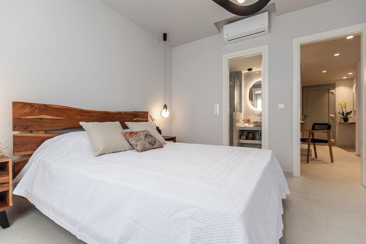 A bedroom with a wooden headboard, a white bedspread, and a bedside table with a lamp.