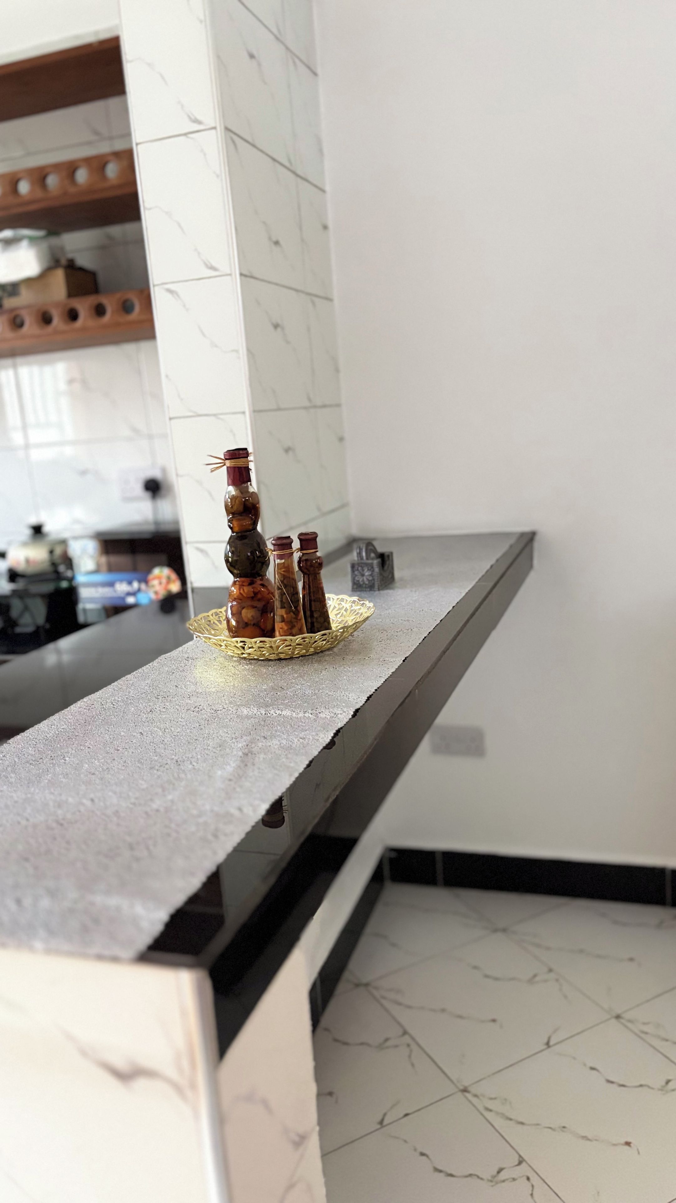 Un piano di lavoro in cucina con un porta bottiglie in vetro decorativo che contiene diverse bottiglie.