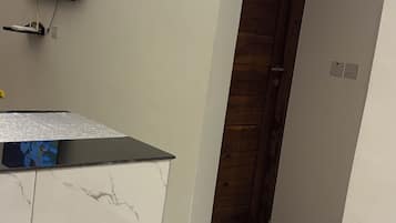 A room with a television mounted on the wall, a wooden door, and a tiled floor with a marble pattern.