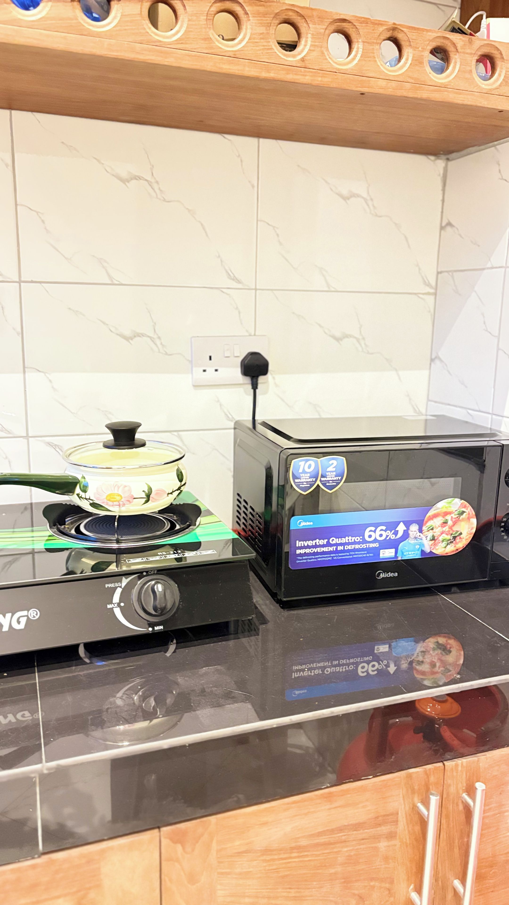 A kitchen with a stove, a microwave, and a pot on the stove.