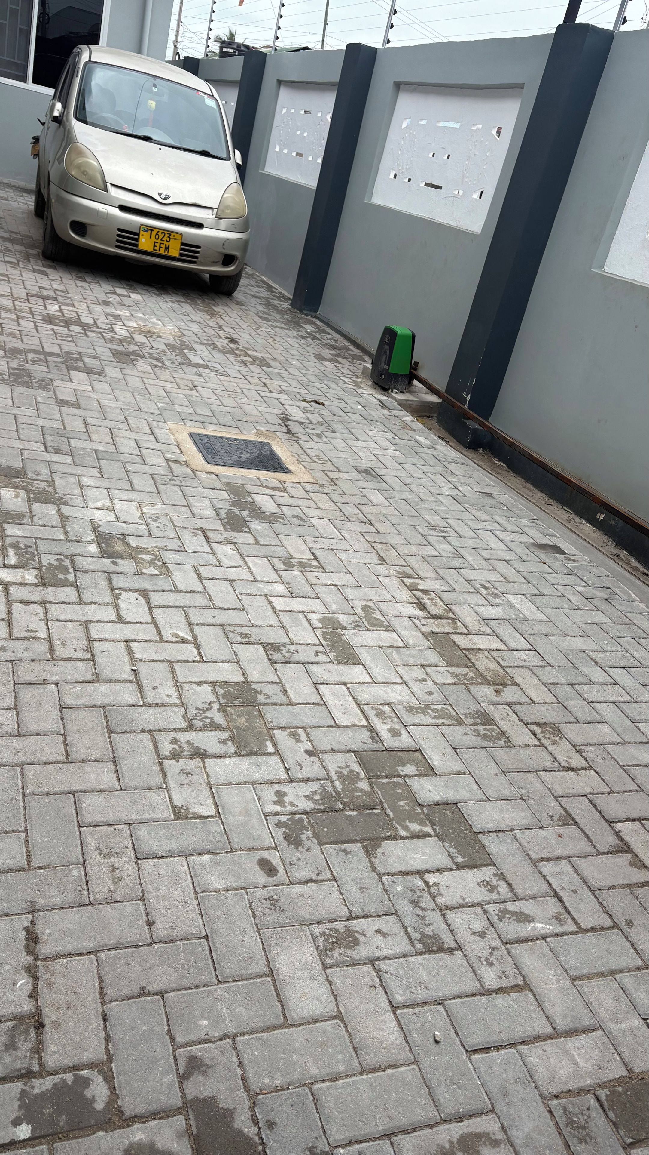Una strada asfaltata con un'auto parcheggiata e un muro con delle finestre.