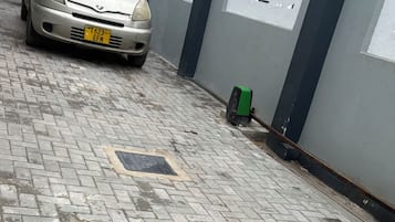 Una strada asfaltata con un'auto parcheggiata e un muro con delle finestre.