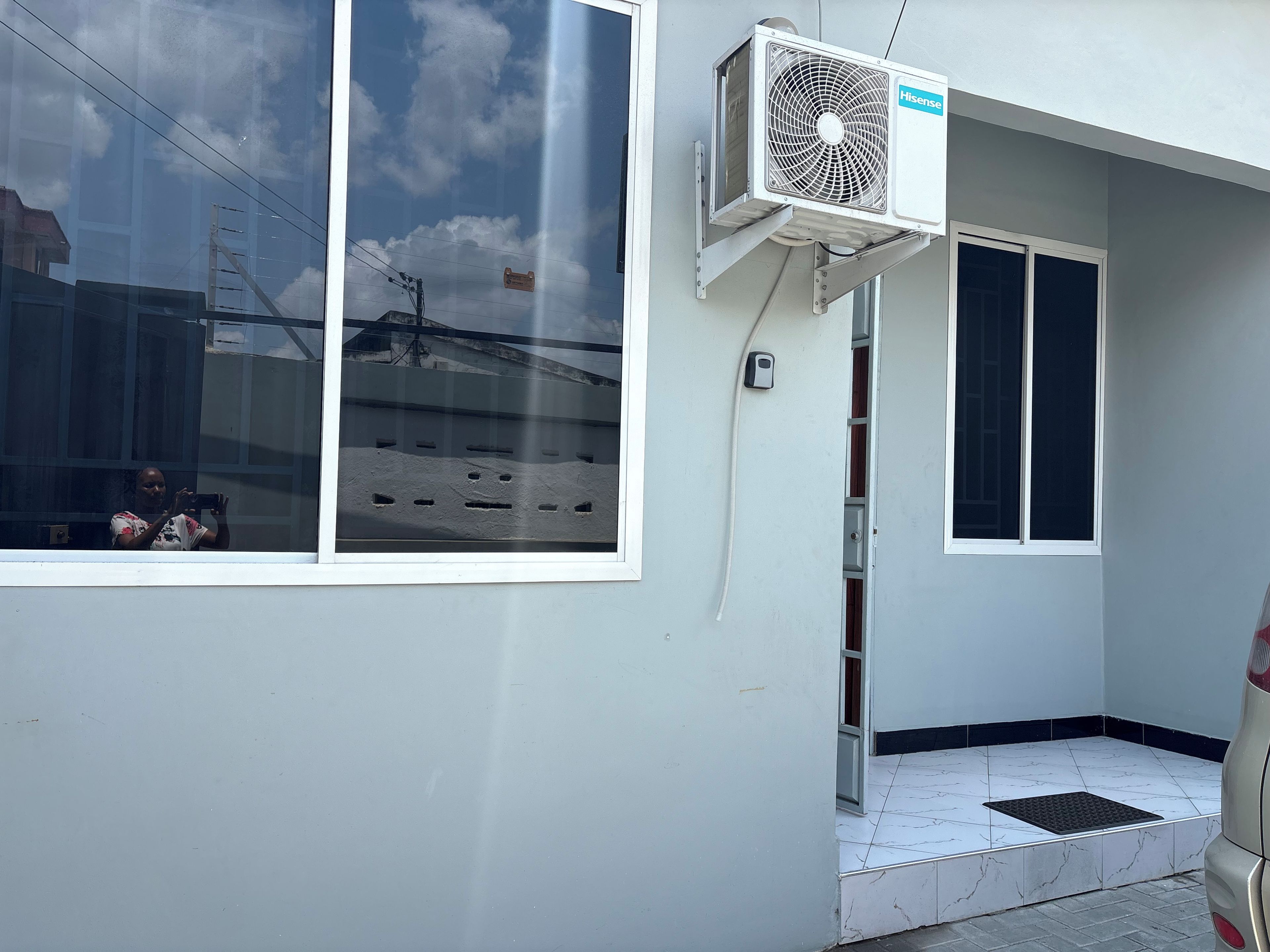 A building with a large window, an air conditioning unit, and a tiled entrance.