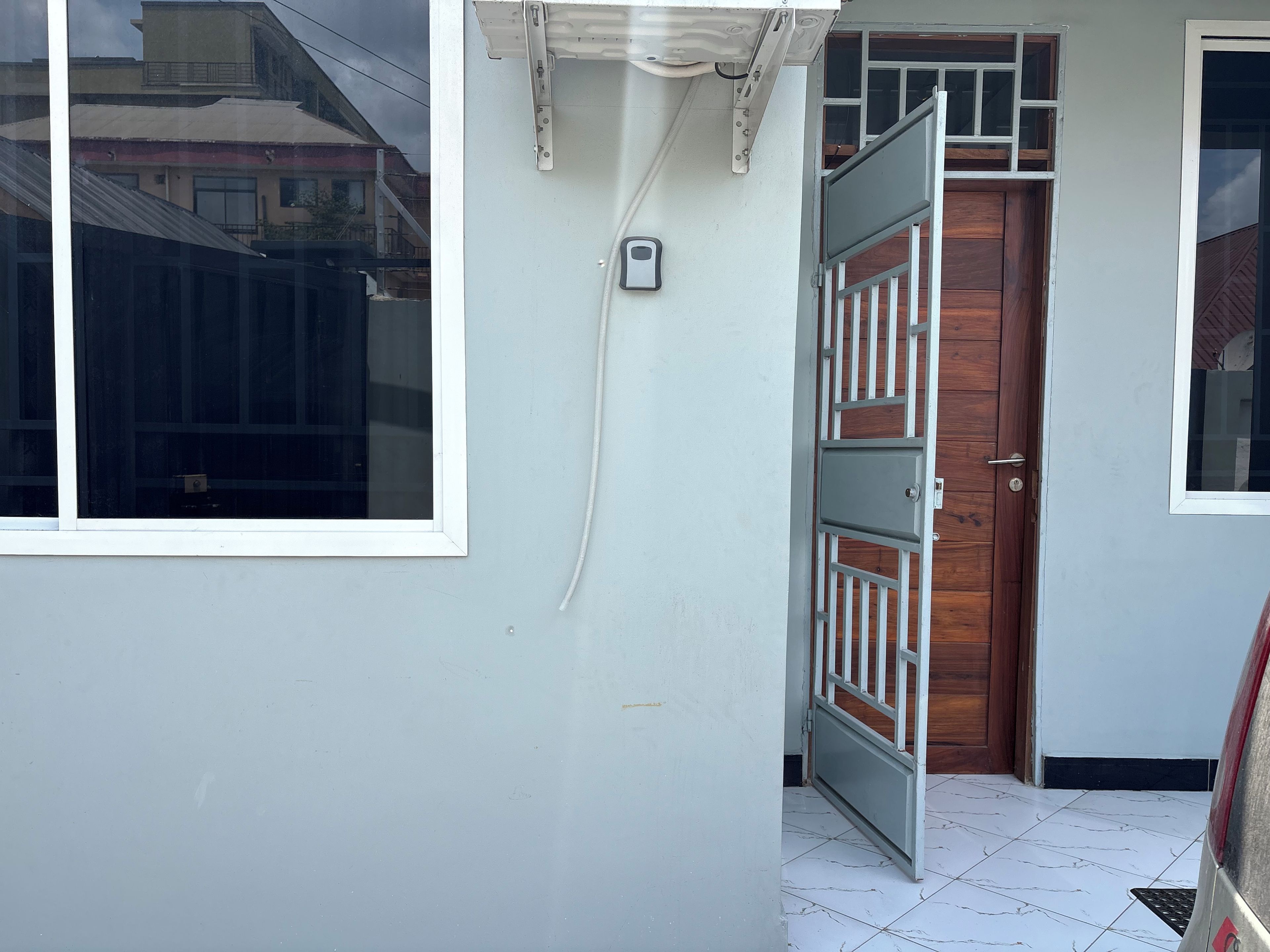 L'ingresso di un edificio con una porta bianca, una finestra e un cancello in metallo.