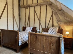 A rustic bedroom with two wooden beds, a sloped ceiling, and exposed wooden beams. - Charming cottage in the heart of the Loir Valley (SAINT ARNOULT)